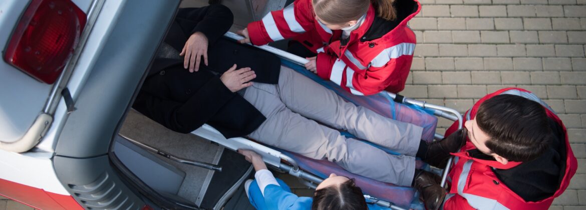 top view of paramedic team moving man on ambulance stretcher into car